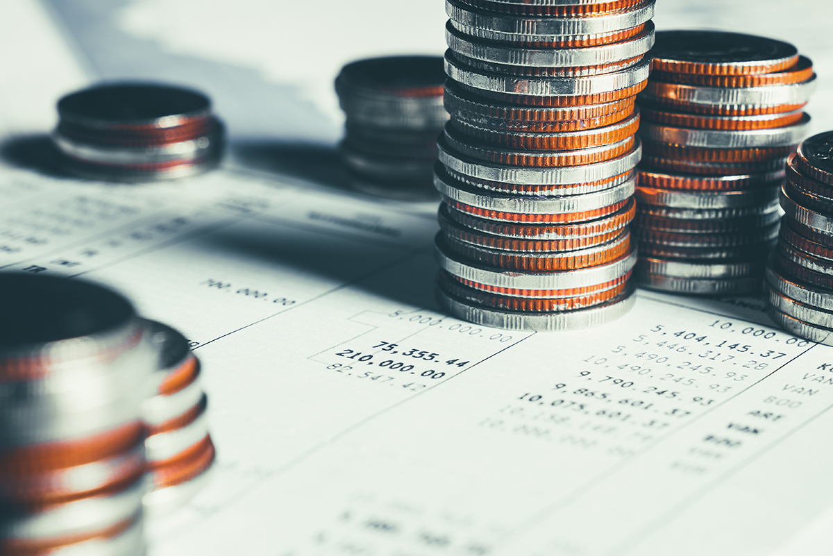 An image of a stack of coins on top of paperwork for financial accounts.