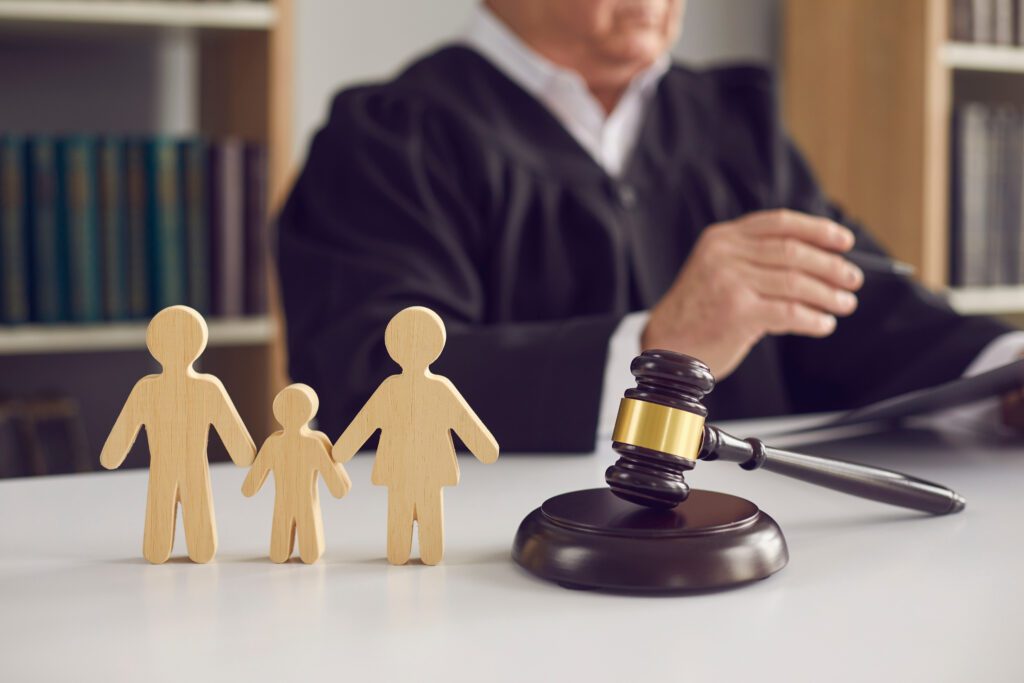 A wooden cutout of a family sitting on a desk by a gavel. 